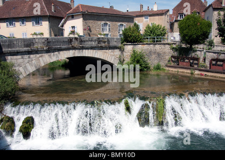 Fiume case alberi weir che scorre veloce ponte di acqua Foto Stock