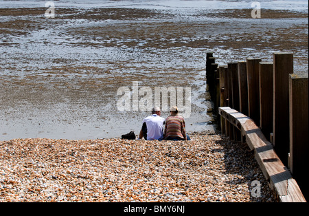 Un maschio e femmina seduto su di una spiaggia di ciottoli. Foto di Gordon Scammell Foto Stock