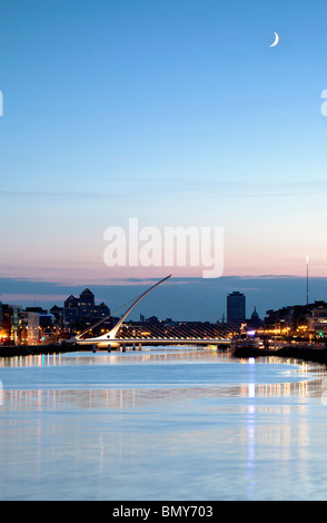 Samuel Beckett Bridge, che attraversano il fiume Liifey a Dublino illuminata di notte con la luna nel cielo Foto Stock