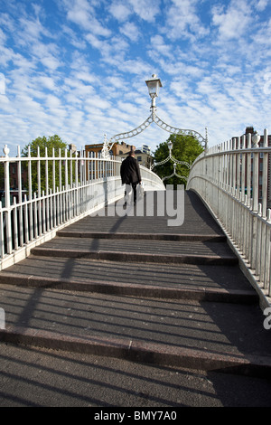 Uomo in una tuta attraversando il Ha'penny ponte che attraversa il fiume Liffey nella capitale Irlandese a Dublino Foto Stock