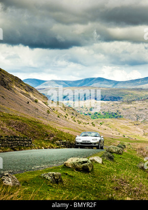 La guida, UK, sport auto guidando su una strada di montagna nel distretto del lago, in un viaggio su strada in Cumbria, England, Regno Unito Foto Stock