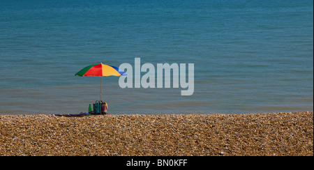 Ombrello coloratissimo isolato su una spiaggia con il mare sullo sfondo. Foto Stock