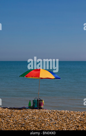 Ombrello coloratissimo isolato su una spiaggia con il mare sullo sfondo. Foto Stock