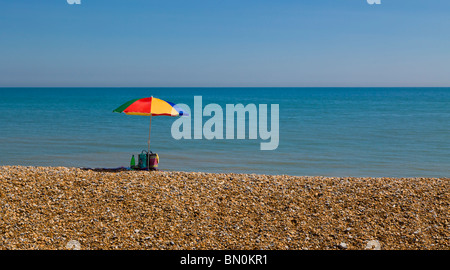 Ombrello coloratissimo isolato su una spiaggia con il mare sullo sfondo. Foto Stock