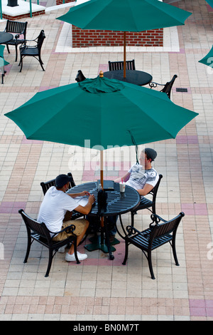 Ybor City, Tampa, FL - Luglio 2009 - Due giovani uomini siedono sotto Ombrello verde a outdoor cafe a Ybor City zona di Tampa, Florida Foto Stock