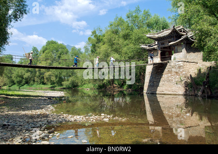 Quattro persone attraversando ponte di legno Shiguzhen Yunnan in Cina Foto Stock