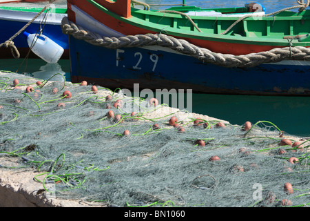 Marsaxlokk, Malta reti da pesca ad asciugare al sole sulla banchina Foto Stock