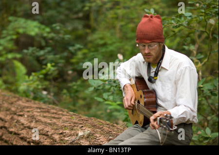 Camping musicisti suonare la chitarra e cantare una melodia in Redwoods Foto Stock