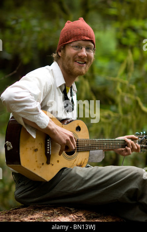 Camping musicisti suonare la chitarra e cantare una melodia in Redwoods Foto Stock