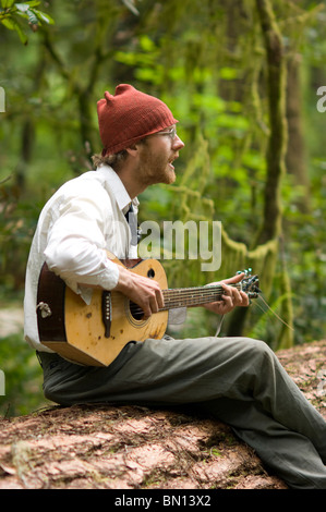 Camping musicisti suonare la chitarra e cantare una melodia in Redwoods Foto Stock