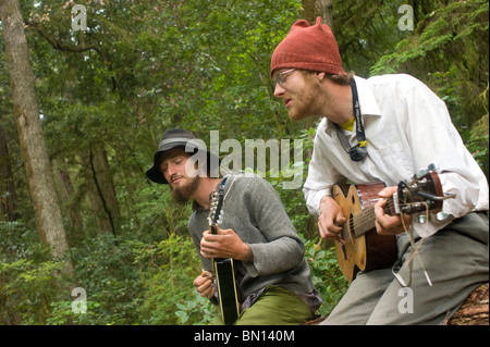 Camping musicisti suonare la chitarra e cantare una melodia in Redwoods Foto Stock