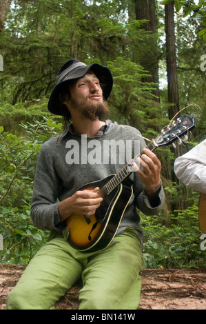 Camping musicisti suonare la chitarra e cantare una melodia in Redwoods Foto Stock