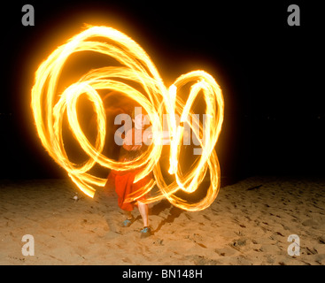 Persona gira il fuoco o danze di fuoco di notte sulla spiaggia Foto Stock