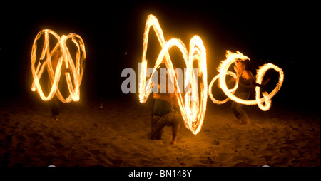 Persona gira il fuoco o danze di fuoco di notte sulla spiaggia Foto Stock