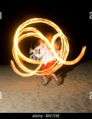 Persona gira il fuoco o danze di fuoco di notte sulla spiaggia Foto Stock