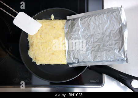 La prima colazione di patate, per home le patatine fritte o roesti svizzero, in un pacchetto di alluminio, pronto a cuocere in una padella. Convenience Food. Foto Stock