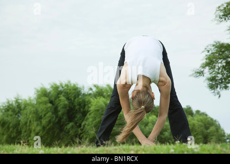 La donna lo stiramento in posizione di parcheggio Foto Stock