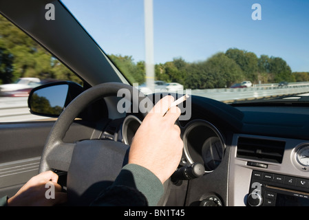 Fumare una sigaretta durante la guida Foto Stock