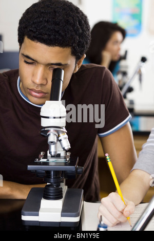 Studente di scuola superiore guardando attraverso il microscopio Foto Stock