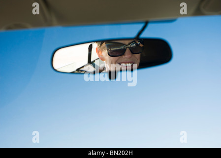 Volto di donna riflessa in specchietto retrovisore Foto Stock