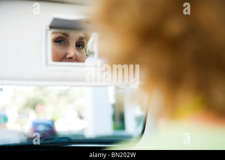 La donna in auto guardando a sé nella visiera specchietto di cortesia Foto Stock