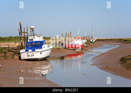 Barche spiaggiata a bassa marea in un torrente di marea a Thornham, Norfolk, Inghilterra England Regno Unito. Foto Stock