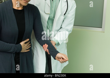 Medico tenendo braccio del paziente e aiutandola a piedi Foto Stock