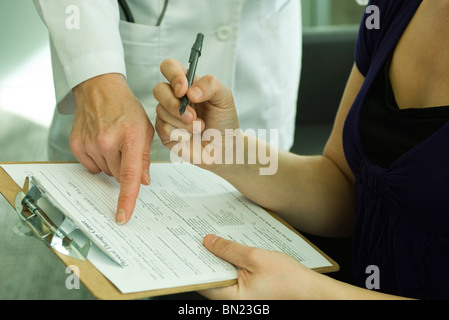 Medico che assiste il paziente con il completamento della documentazione medica Foto Stock