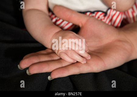 Un bambino mano nella sua madre la mano Foto Stock