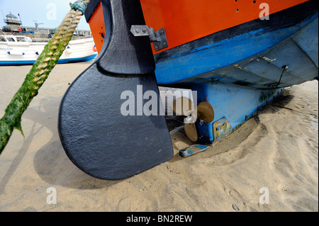 Close up della barca da pesca di timone ed elica in sabbia a bassa marea Foto Stock