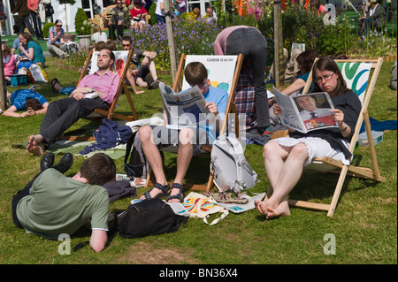 Persone che leggono i giornali e rilassante sotto il sole a Hay Festival 2010 Hay on Wye Powys Wales UK Foto Stock