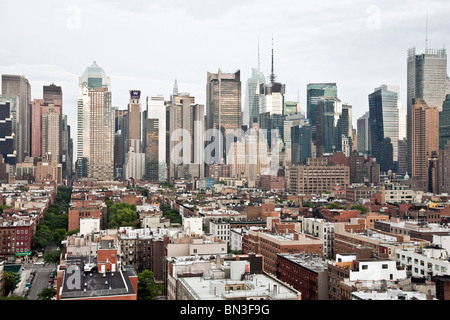 Vista guardando verso est al tramonto su tetti in basso del vecchio alloggiamento magazzino in Hells cucina per metà dello skyline di Manhattan rivestimento torri 8th Avenue e Broadway NYC Foto Stock