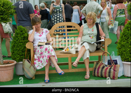 Due Signore seduto sul banco di legno con lettura a Hay Festival 2010 Hay on Wye Powys Wales UK Foto Stock