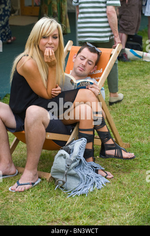 Giovane uomo libro lettura seduto nella sedia sdraio con la giovane donna bionda seduto sul suo giro a Hay Festival 2010 Hay on Wye Powys Galles Foto Stock