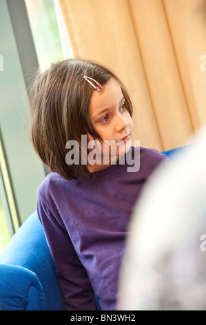 Giovane ragazza seduta su un divano Foto Stock