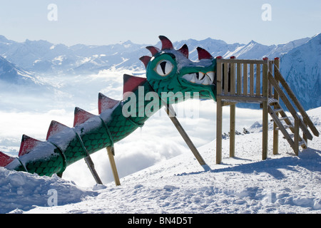 Parco giochi per bambini dragon slide a snowy Niederhorn Swiss vista montagne Foto Stock
