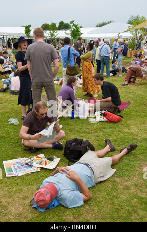 Due uomini uno addormentato altri leggendo un giornale sdraiati sull'erba a Hay Festival 2010 Hay on Wye Powys Wales UK Foto Stock