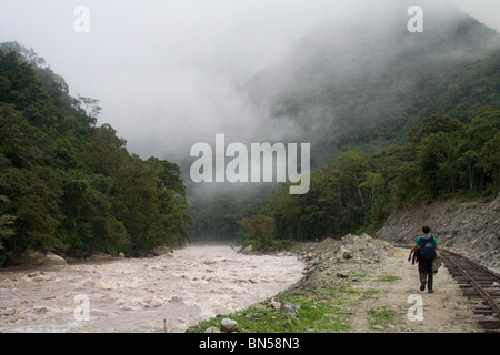 Backpacker in piedi tra il fiume e i binari della ferrovia. Foto Stock