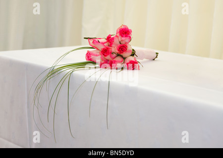 Un matrimonio bouquet di rose rosa su un tavolo bianco con un rettangolo di selezione dello sfondo. Foto Stock