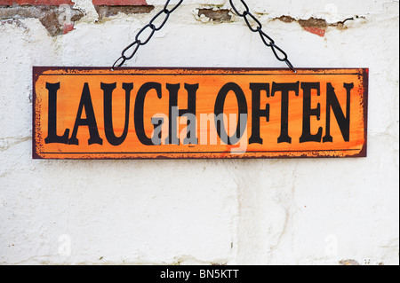 Ridere spesso. Il vecchio giardino di metallo indicazioni su un dipinto di un muro di mattoni Foto Stock