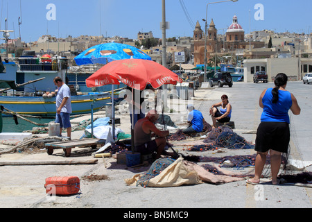 Rammendo delle reti da pesca sulla banchina al porto di Marsaxlokk, sud di Malta, Mediterraneo, Europa Foto Stock