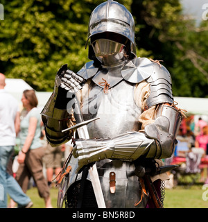 Uomo di indossare tuta di armor al castello verde, Hereford, Regno Unito. La rievocazione medievale cavaliere con un broadsword. Foto Stock