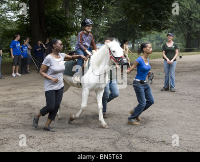 I bambini disabili ricevono terapia evolutiva imparare a cavalcare cavalli, noto come l'ippoterapia. Prospect Park di Brooklyn, NY Foto Stock