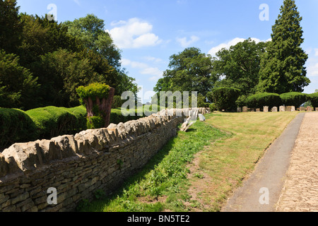 Tagliata e sagomata yew siepe di Turvey casa nel villaggio di desiderabile di Turvey accanto al sagrato a parete, Bedfordshire, Regno Unito Foto Stock