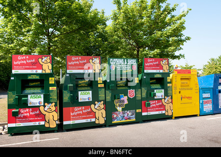 Fila di abbigliamento cassonetti per il riciclaggio in un supermercato Asda parcheggio auto. Foto Stock