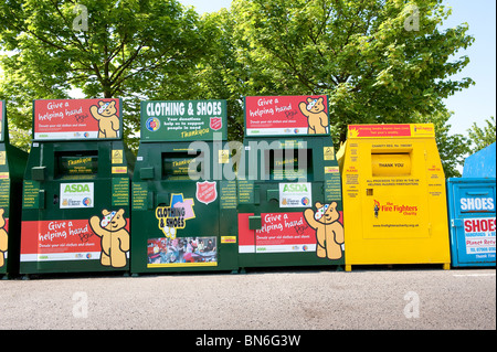 Fila di abbigliamento cassonetti per il riciclaggio in un supermercato Asda parcheggio auto. Foto Stock