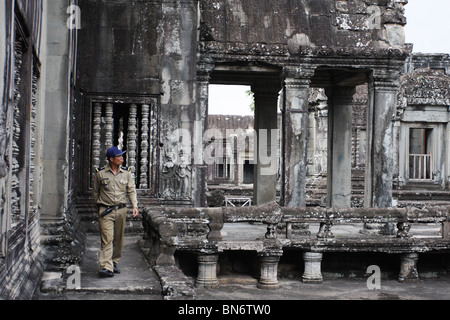 Un uomo di polizia tra devatas nel cortile interno di Angkor Wat, Cambogia. Foto Stock