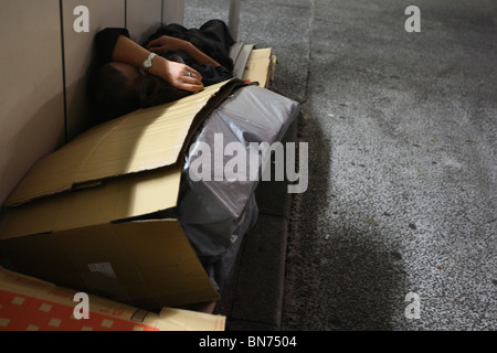 Senzatetto uomini sonno agitato in scatole di cartone per le strade di Tokyo, Giappone. Foto Stock