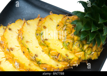 Mature vibrante a fette di ananas su una piastra nera Foto Stock