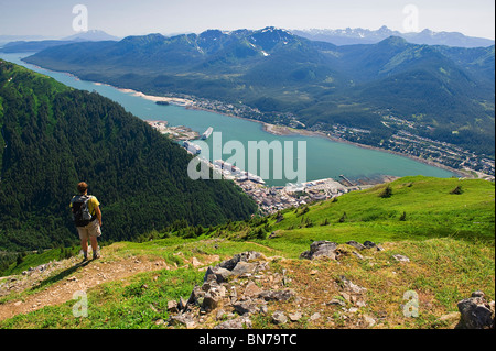 Un escursionista prende in vista del canale Gastineau, Isola di Douglas e il centro cittadino di Juneau dalla sommità del Mt. Juneau in Alaska Foto Stock